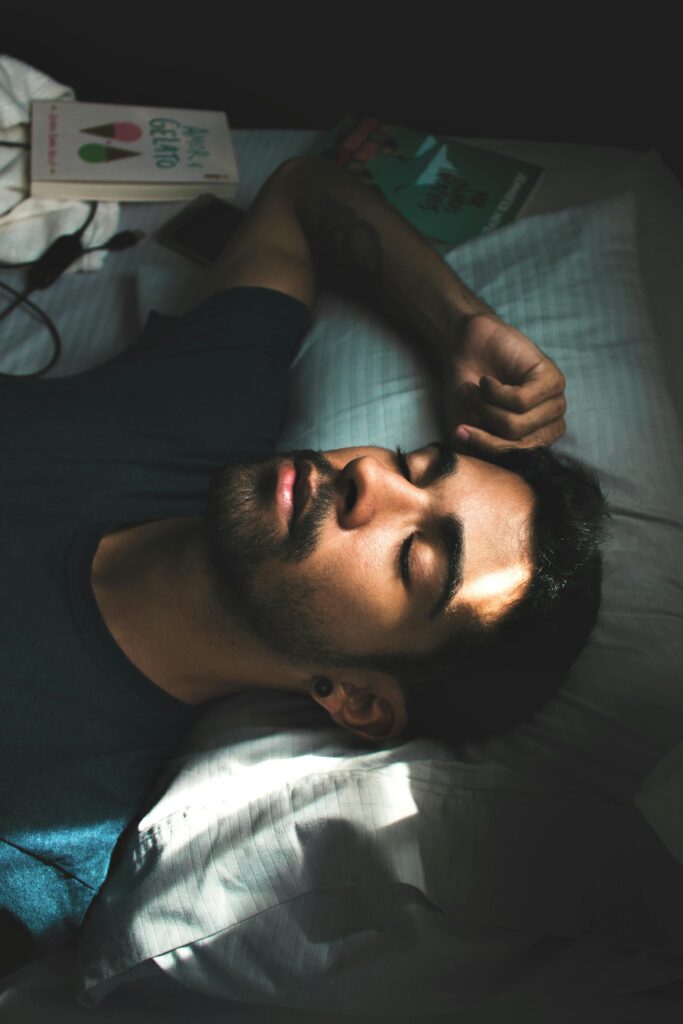 A serene portrait of a young man sleeping peacefully in a sunlit bedroom setting.